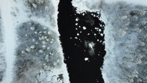 Schneebedeckte Landschaft mit einem dunklen Fluss