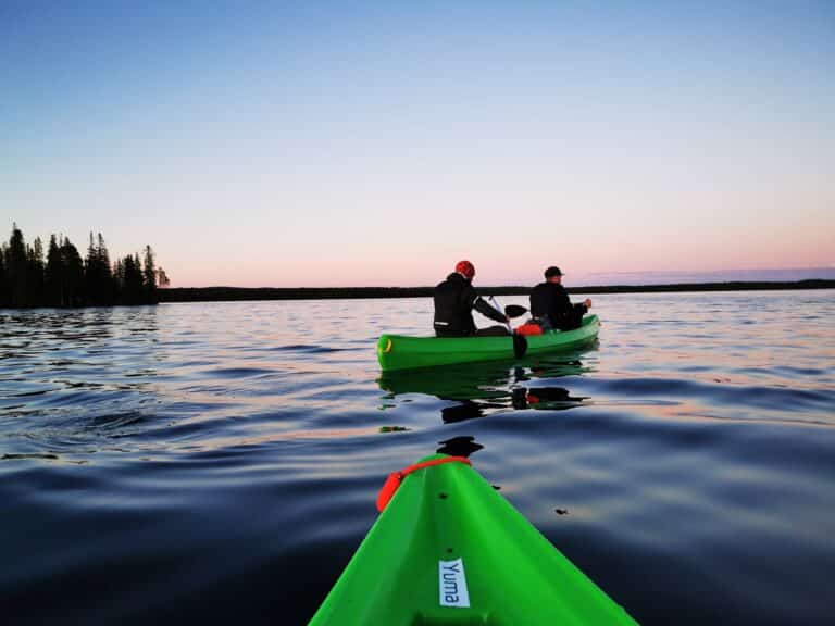 Two people are paddling in green kayaks on the lake