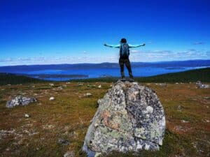 Wanderer auf einem Felsen mit Aussicht auf den See