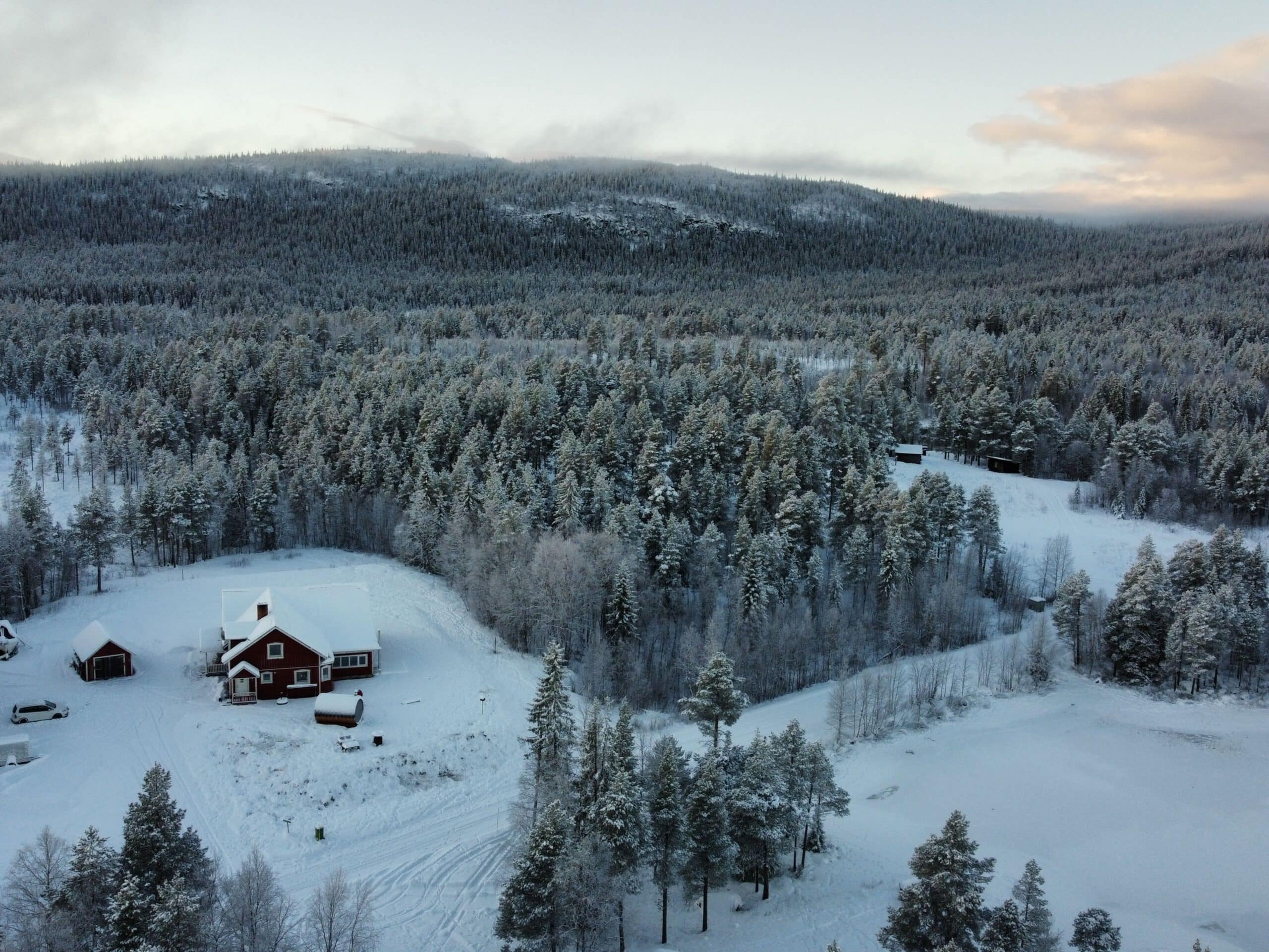 Schneebedeckte Landschaft mit rotem Haus und Wäldern