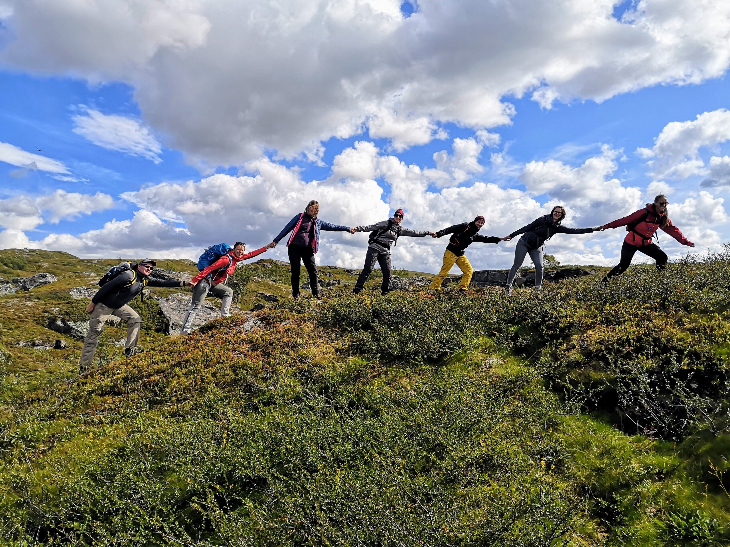 Sechs Personen wandern und halten sich an den Händen.