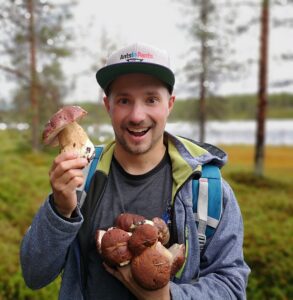 Man presenterar färska svampar i skogen