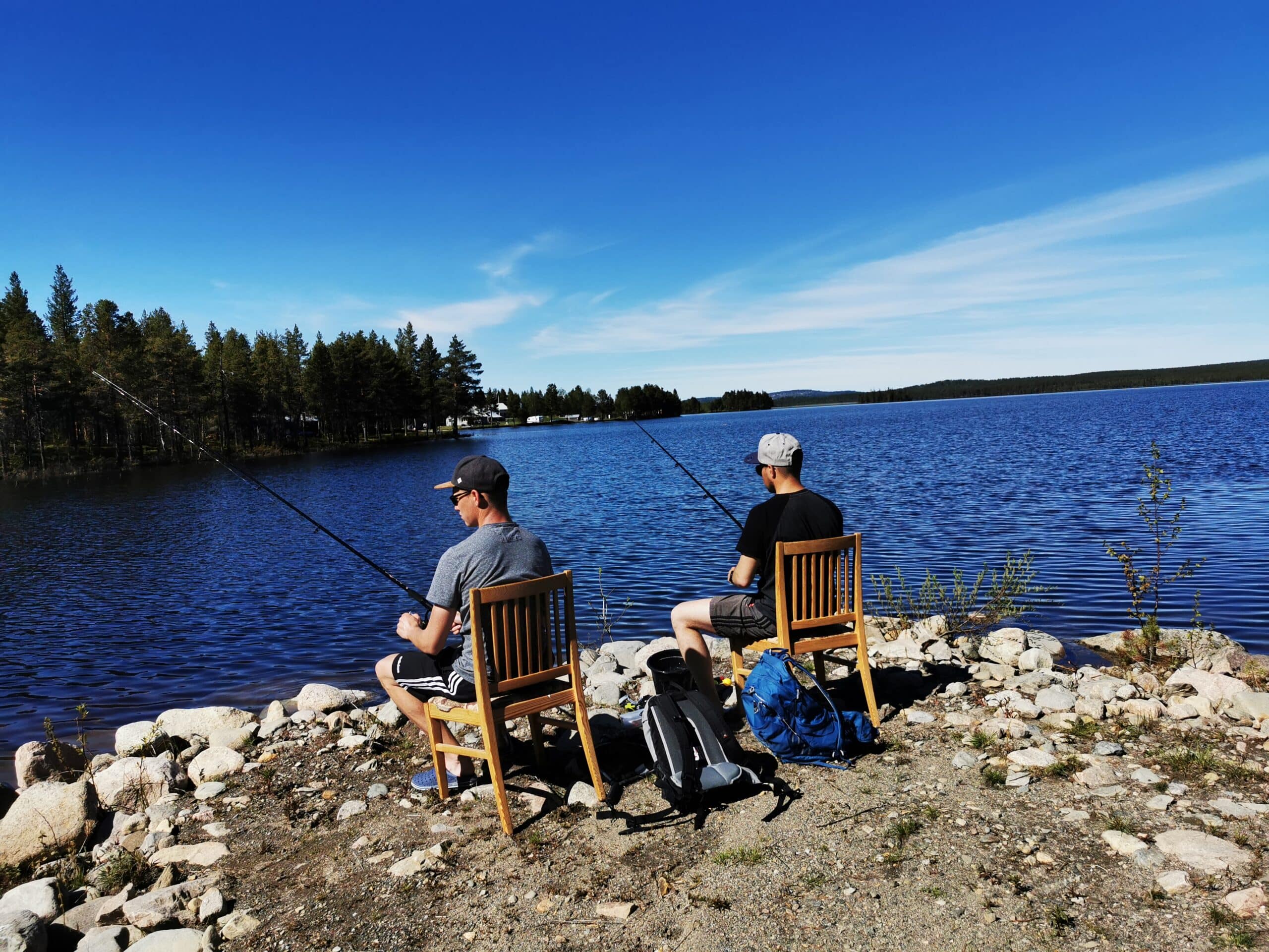 Zwei Personen angeln am ruhigen Wasser.