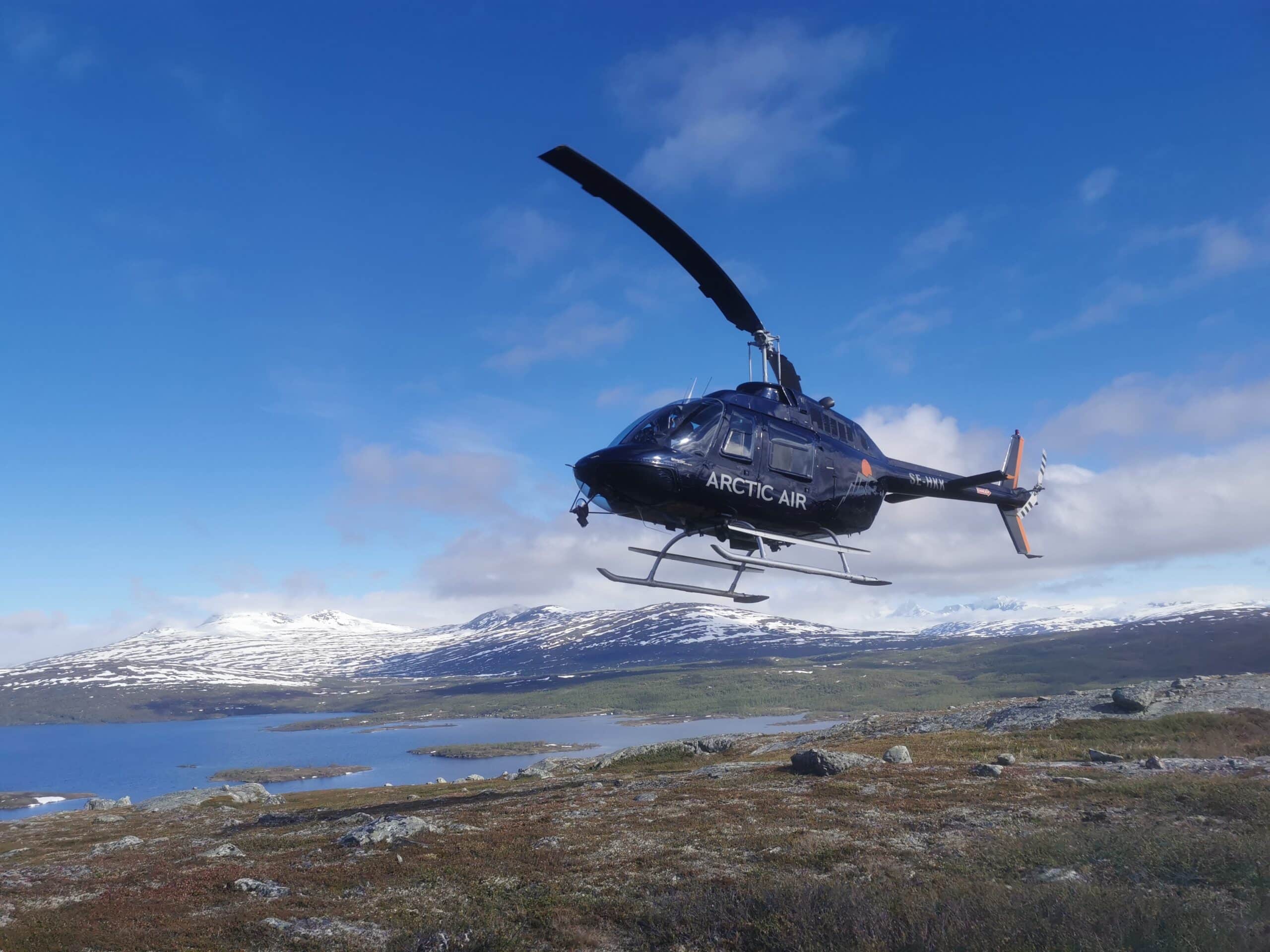 Schwarzer Hubschrauber über schneebedecktem Bergland