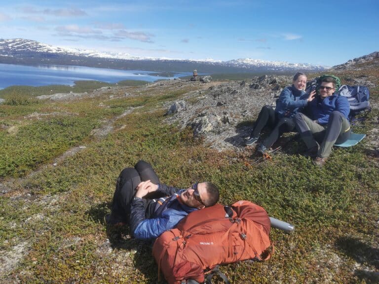 Three people are enjoying the scenery while hiking.