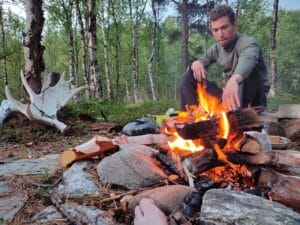 Mann sitzt am Lagerfeuer in der Natur