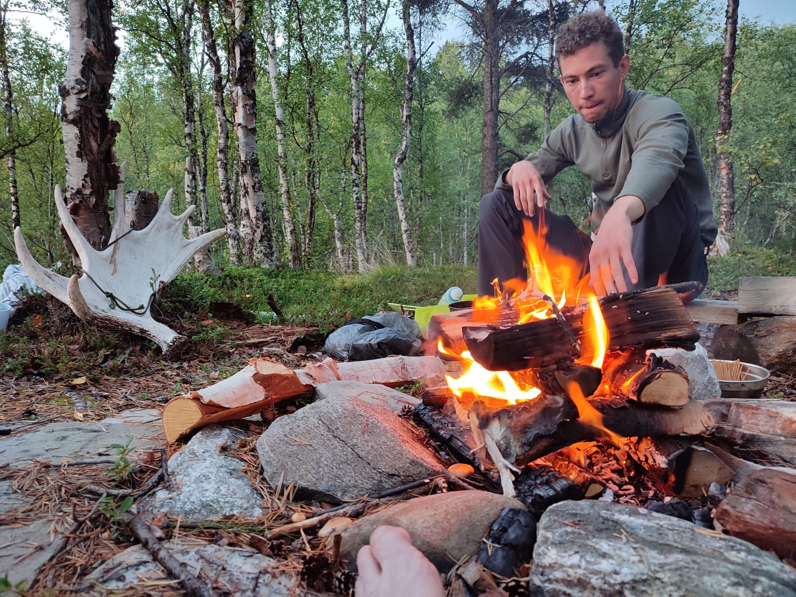 Mann sitzt am Lagerfeuer in der Natur