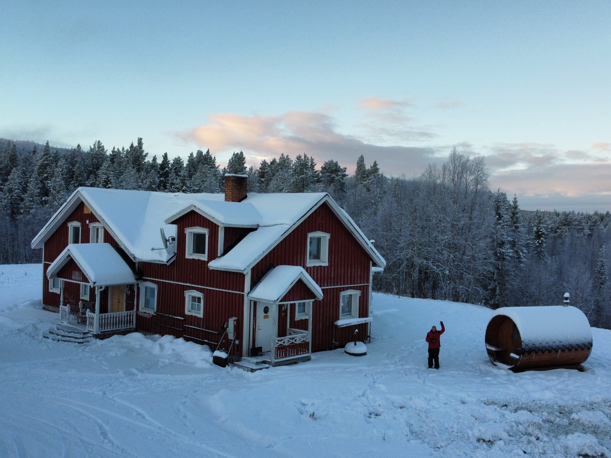 Rotes Winterhaus mit Schnee und Person draußen