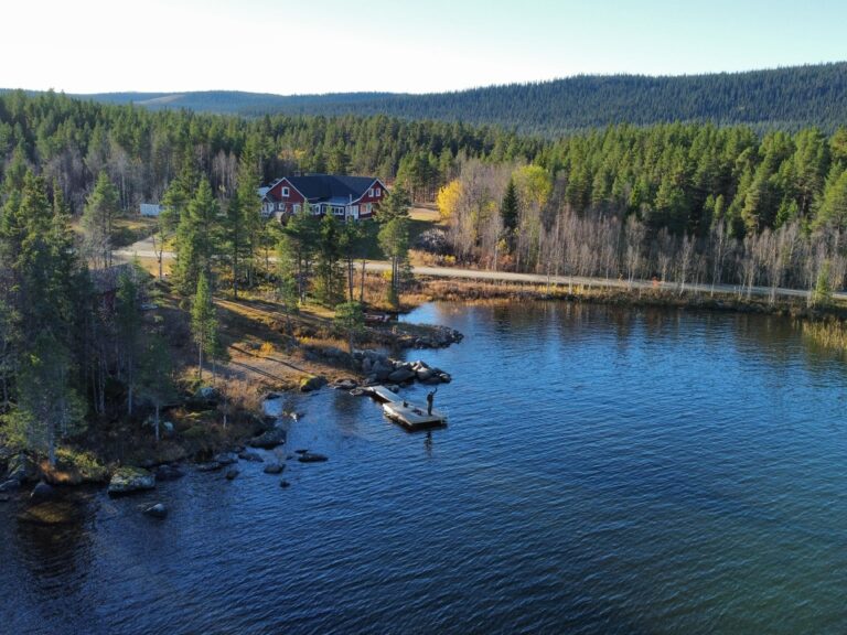 A red cabin by a quiet lake surrounded by nature