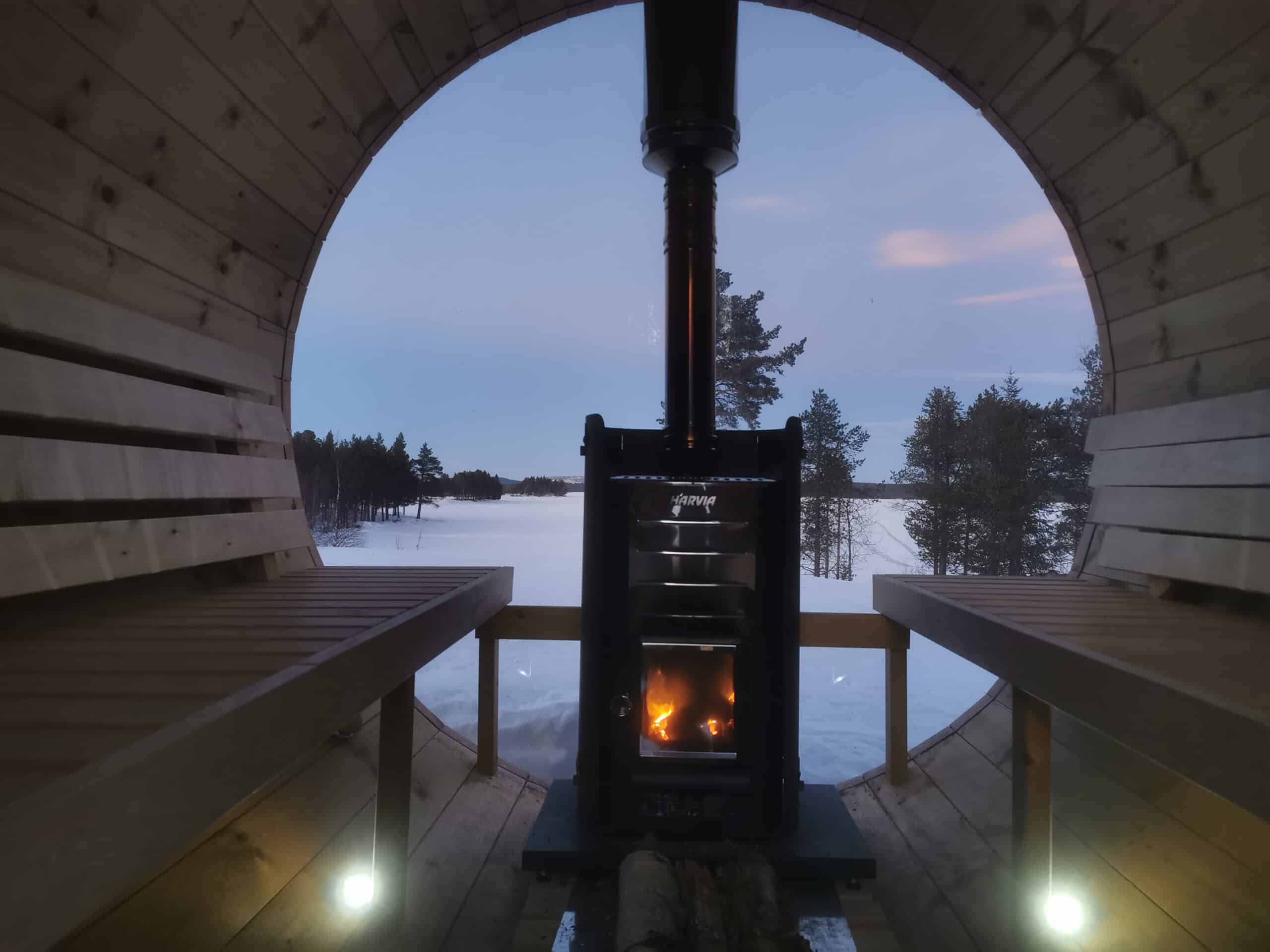 Blick auf Sauna mit Kamin und winterlicher Landschaft.