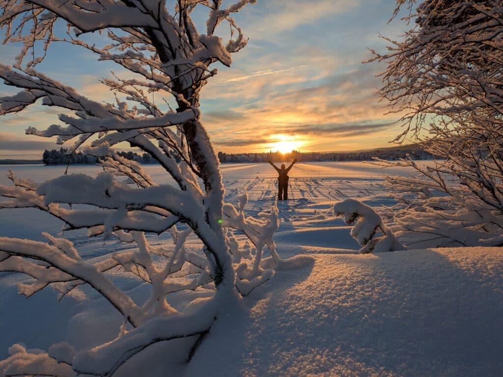 Sonnenuntergang über verschneiter Landschaft mit Person
