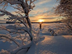 Sonnenuntergang über verschneiter Landschaft mit Person