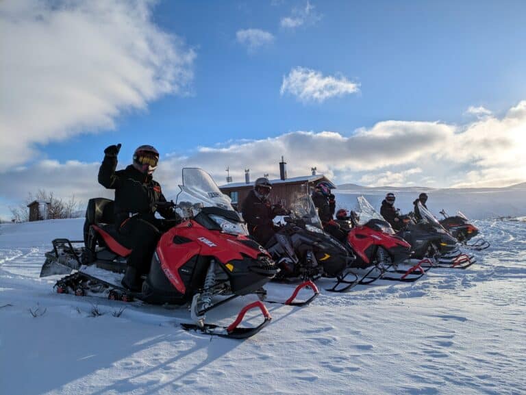 Motorschlittenfahrer im Schnee bei blauem Himmel