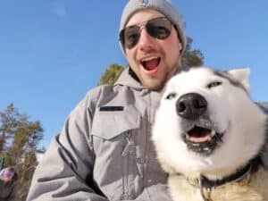 Glücklicher Mensch mit Husky im Schnee.