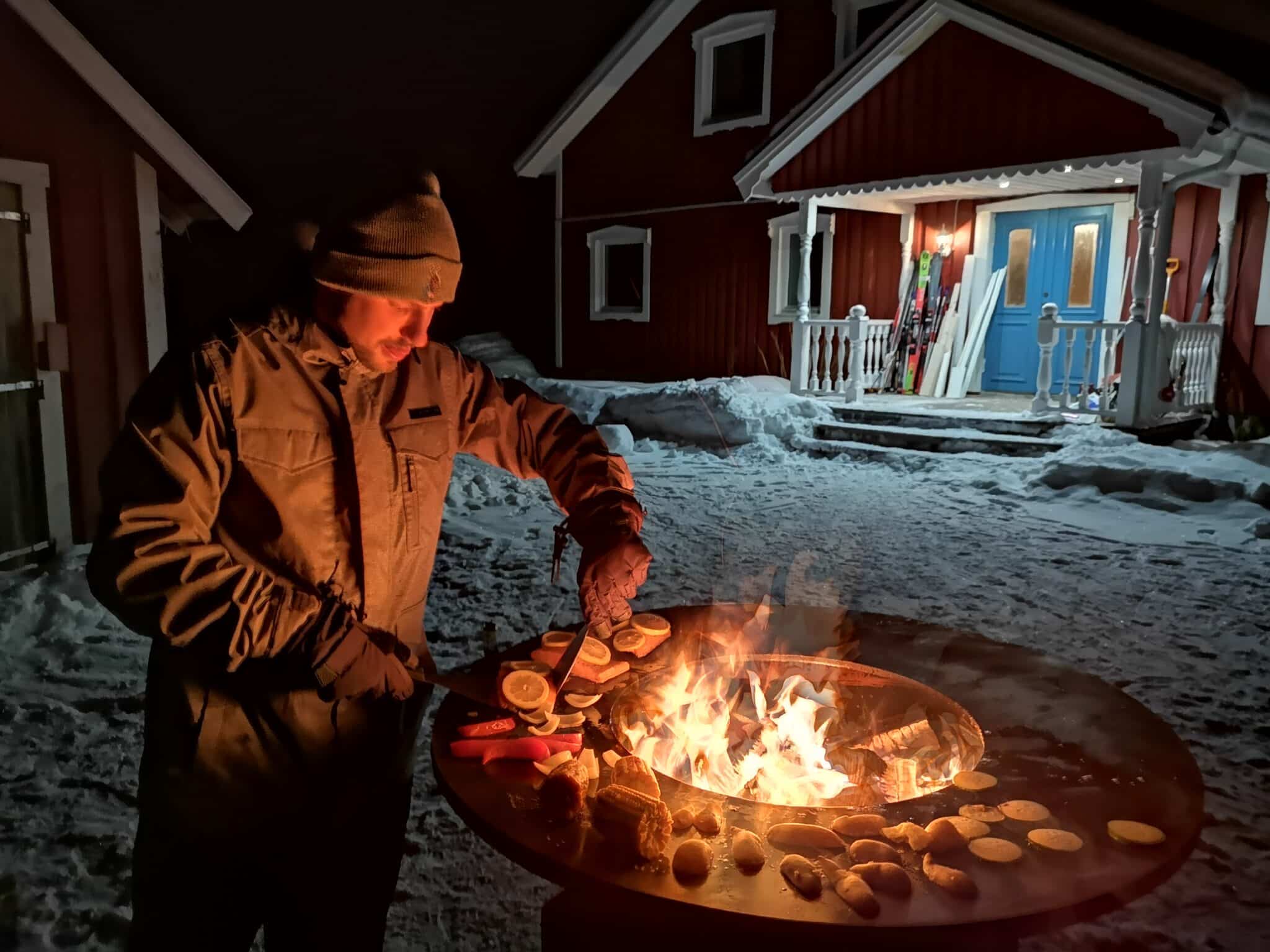Mann bereitet Essen am Feuer im Schnee zu