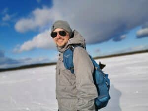 Mann in Winterkleidung mit Sonnenbrille im Schnee