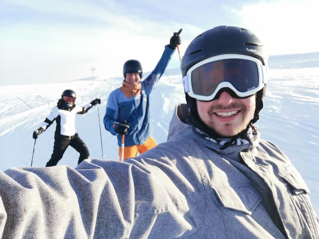 Drei Skifahrer posieren lächelnd im Schnee.