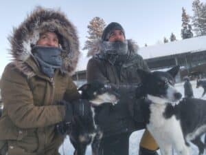 Zwei Personen mit Hunden im Schnee.