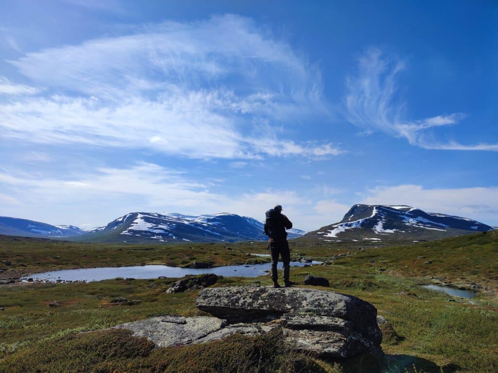 Mensch fotografiert Landschaft mit Bergen und See.