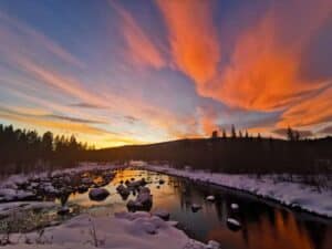 Winterlandschaft mit schneebedecktem Fluss und Sonnenuntergang