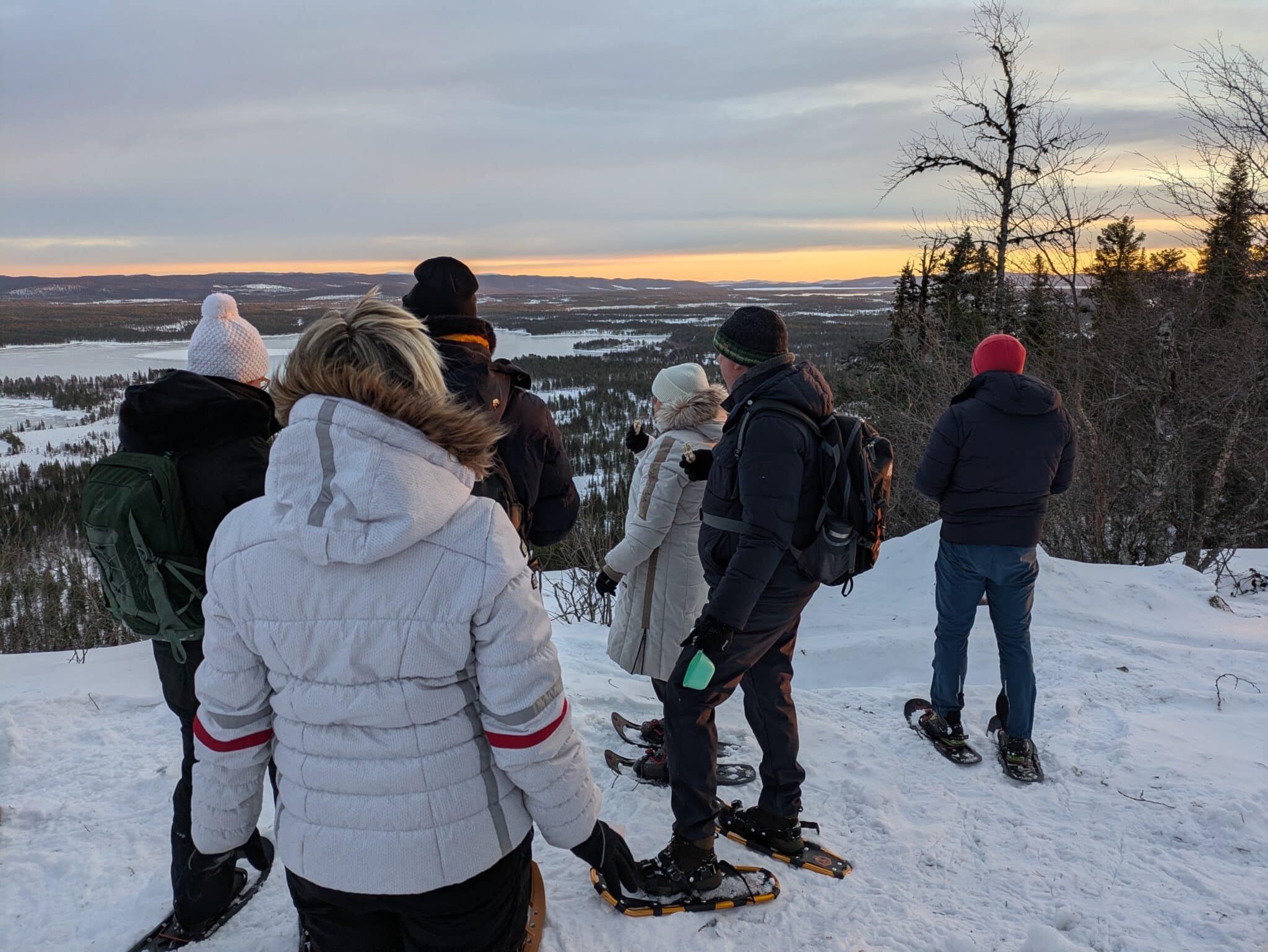 Gruppe beim Schneeschuhwandern mit Aussicht im Winter.