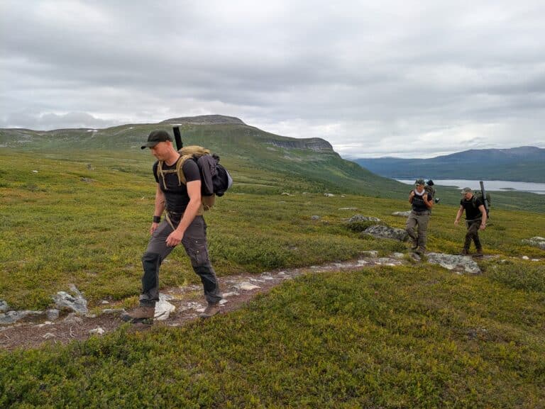 Wanderer auf einem grünen, bergigen Wanderweg.