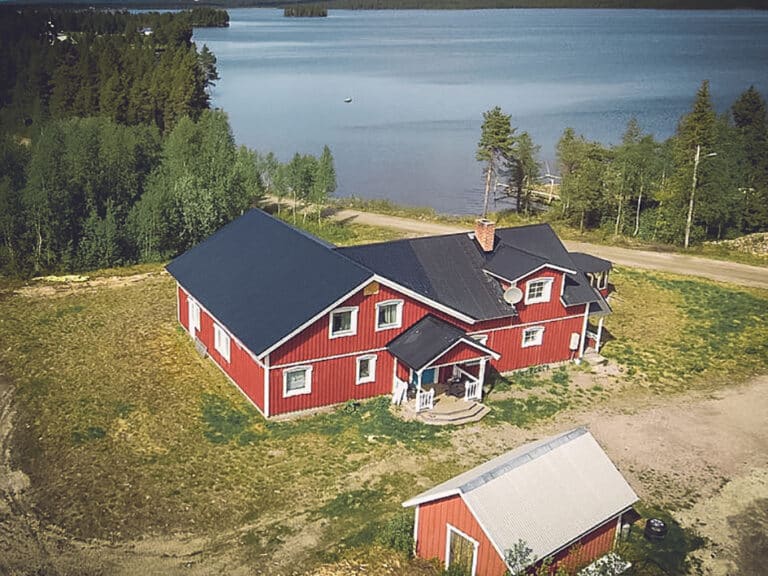 Rotes Haus am See mit Bäumen im Hintergrund